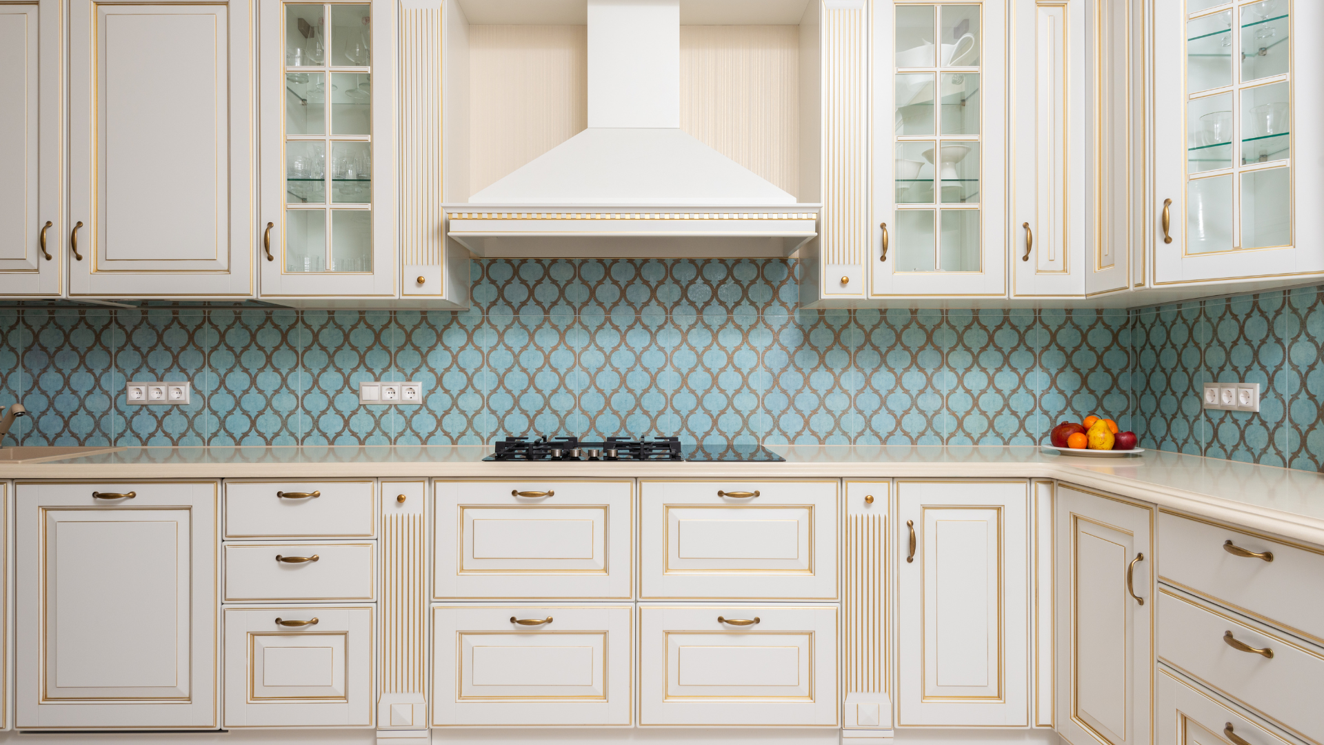 A kitchen with white cabinets and blue tiles on the wall.