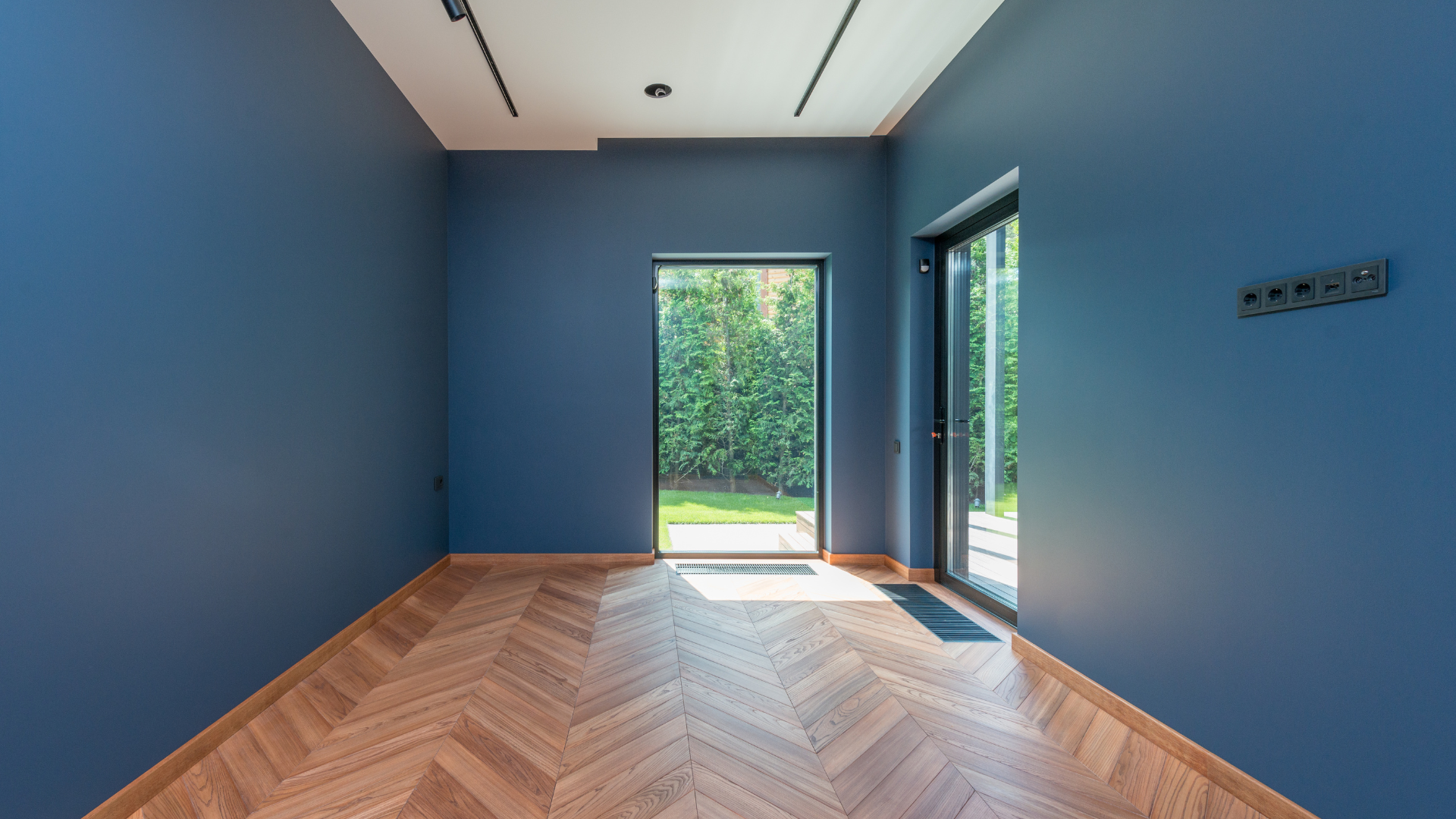 An empty room with blue walls and a wooden floor.