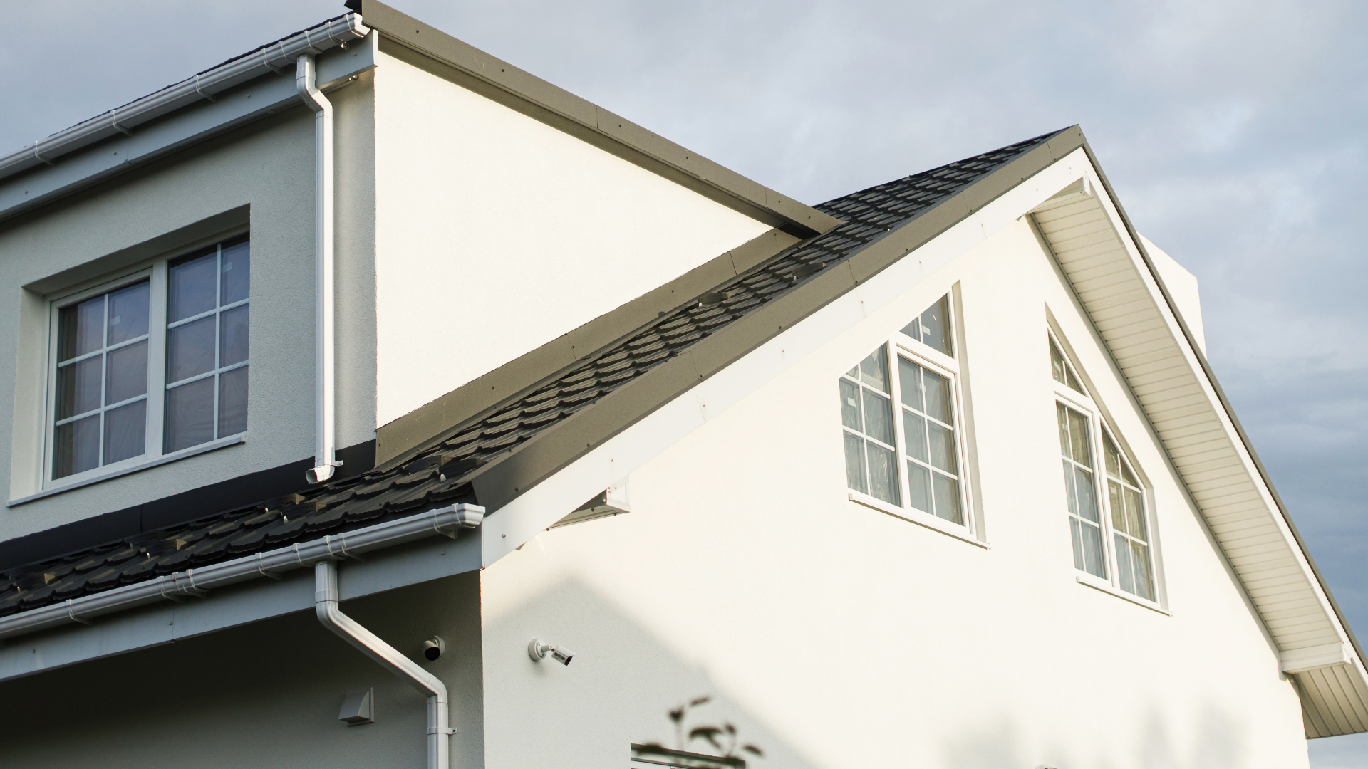 A white house with a roof that has a window on it.