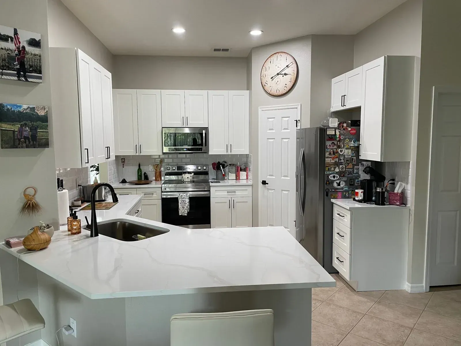 A kitchen with white cabinets and a clock on the wall.