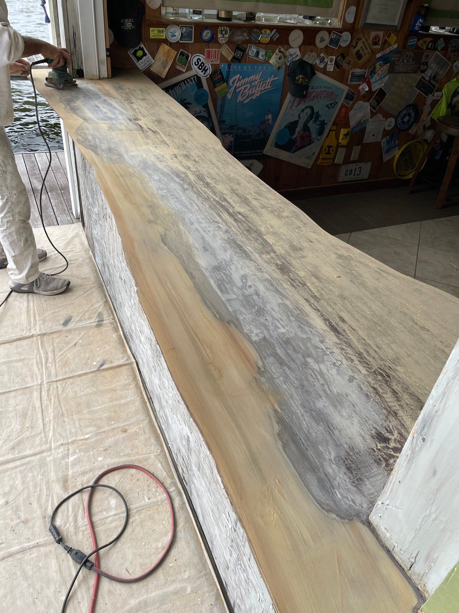 A person is sanding a wooden surface with a sander.