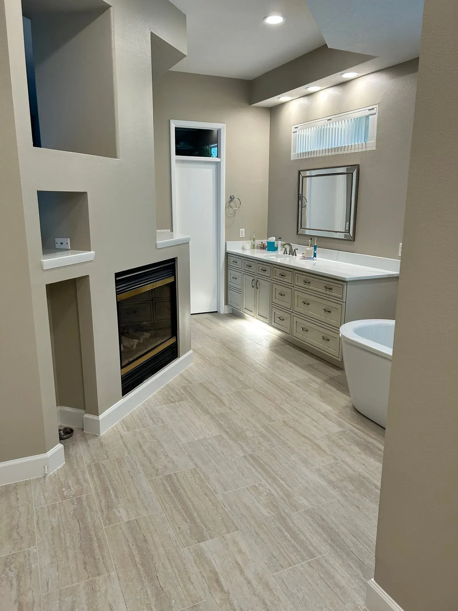 A bathroom with a fireplace , sink , tub and mirror.