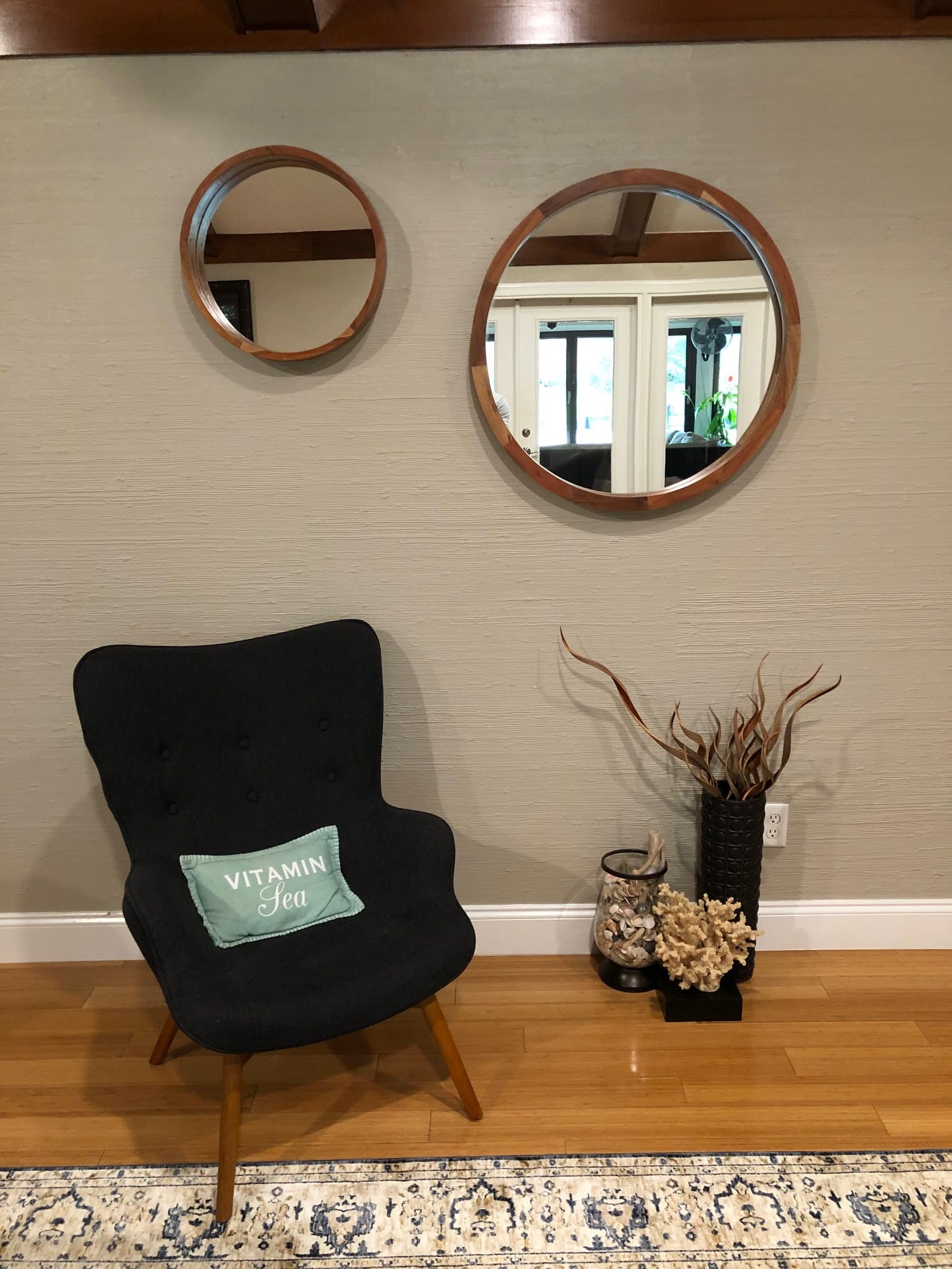 A chair is sitting in a living room next to two mirrors.