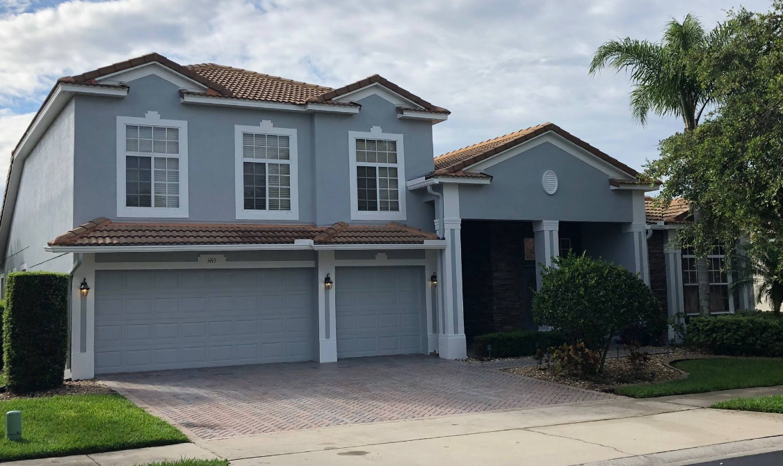 A large blue and white house with two garages and a driveway.