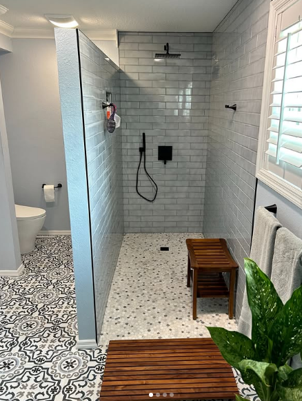 A bathroom with a walk in shower and a wooden bench