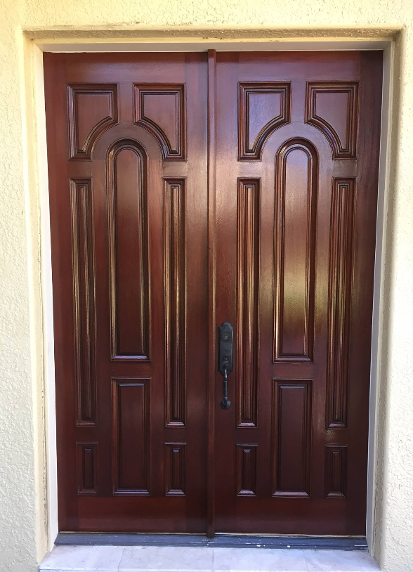 A pair of wooden doors sitting on top of a white wall.