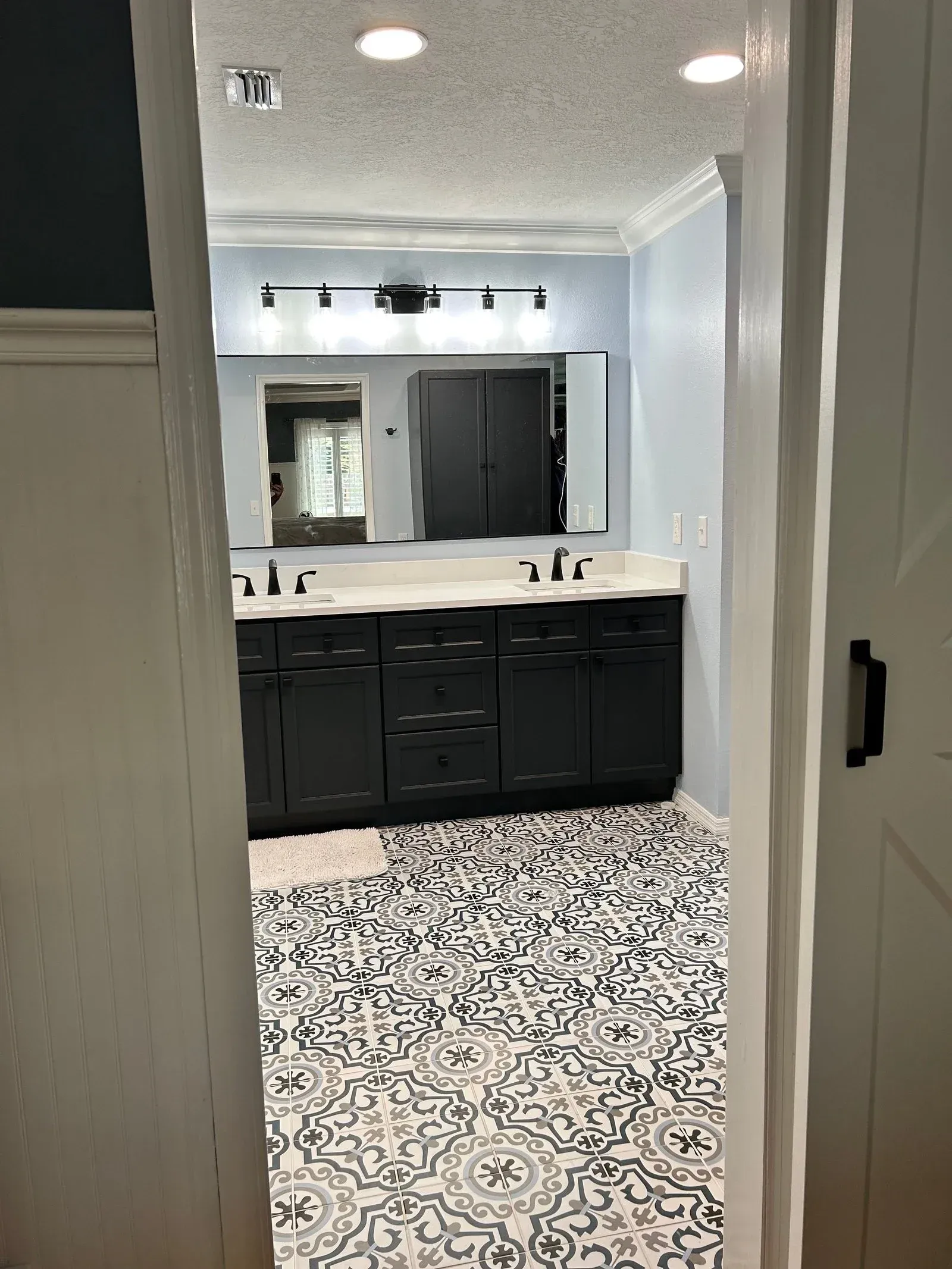 A bathroom with black cabinets and a black and white tile floor.