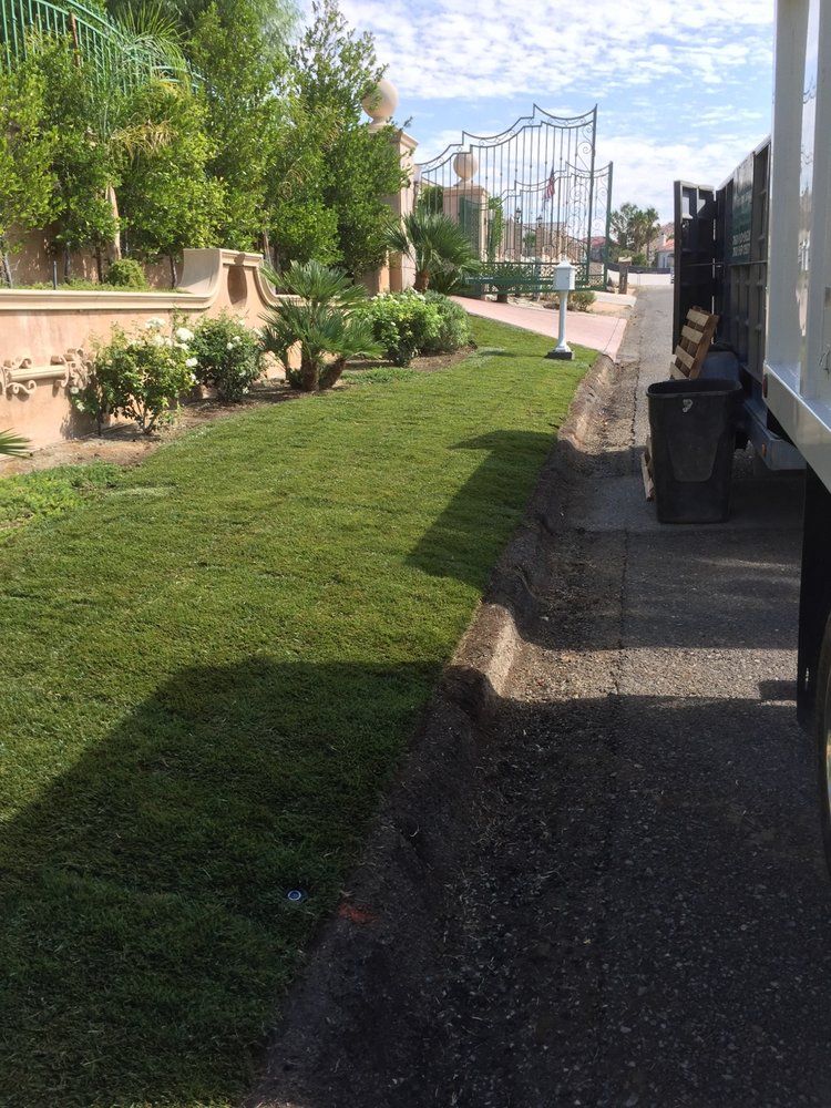 Green grass and landscaping next to a street with a garbage truck.