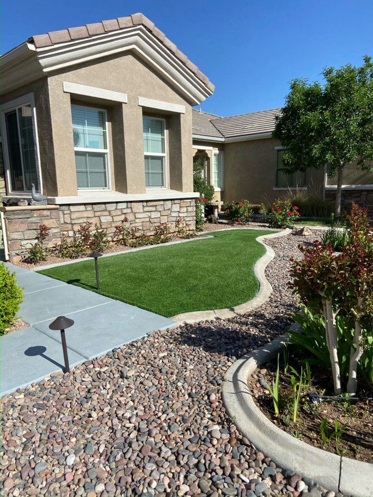 Tan house with manicured lawn, stone path, and flower beds.