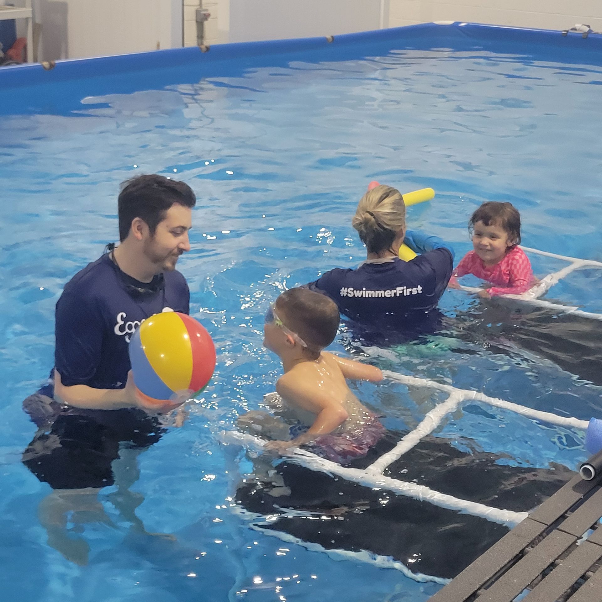 A man is holding a beach ball in a swimming pool