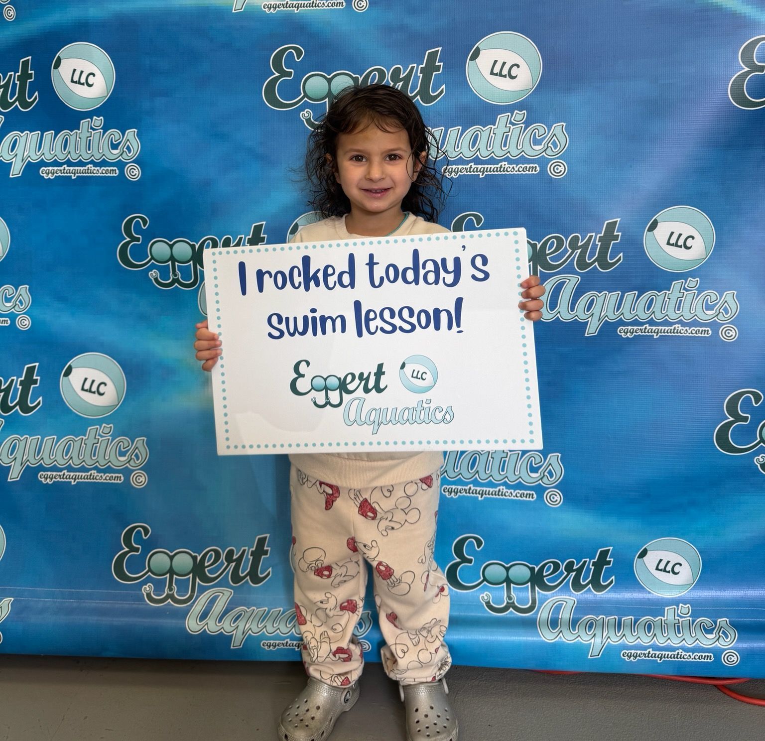 A little girl is holding a sign that says i rocked today 's swim lesson