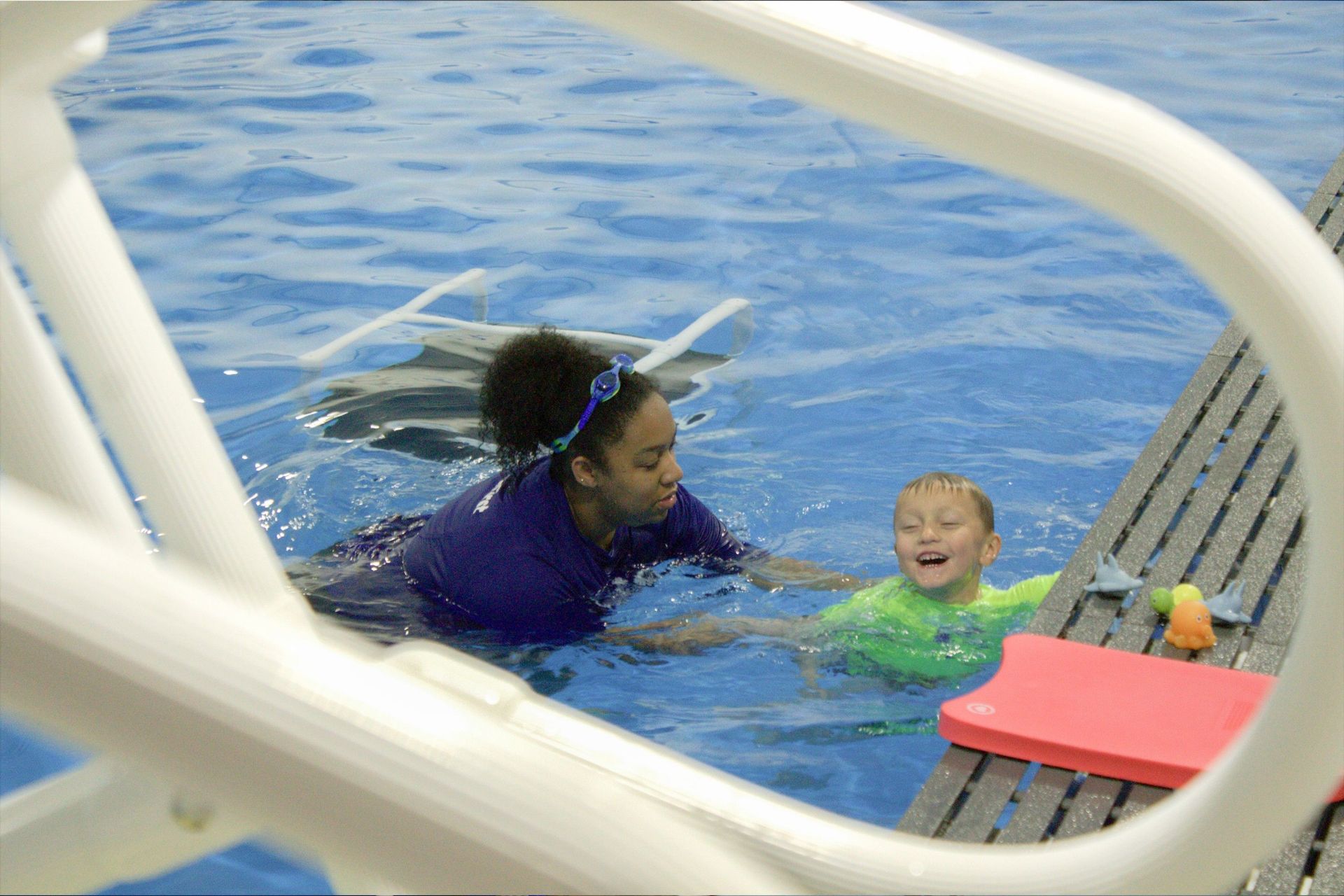 A woman is teaching a child how to swim in a swimming pool.