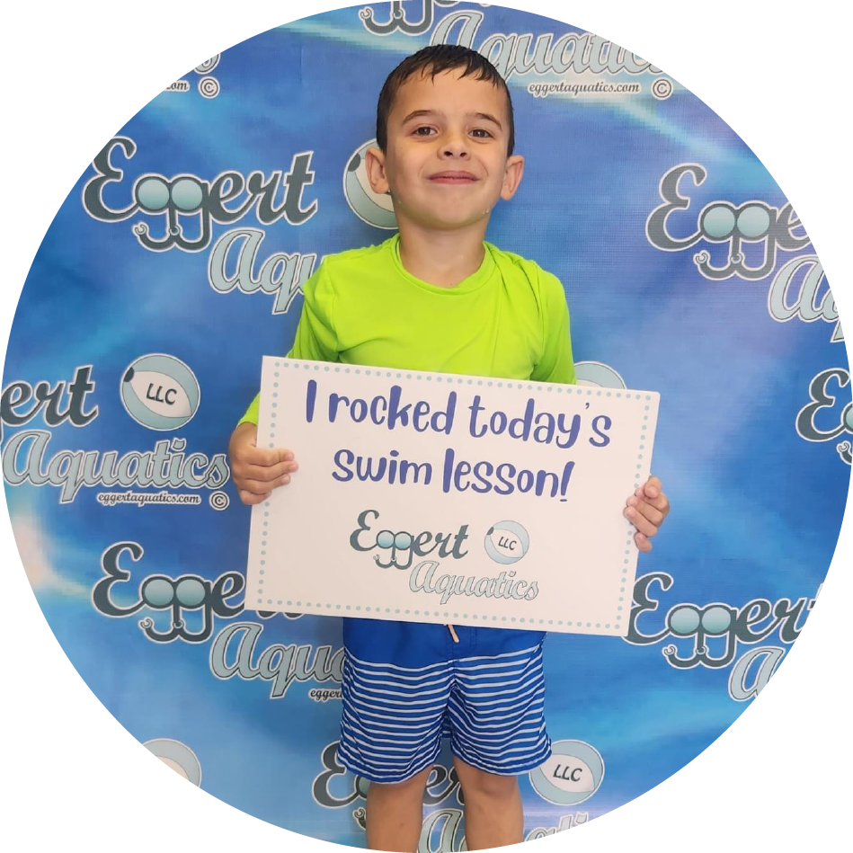 A young boy is holding a sign that says i rocked today 's swim lesson