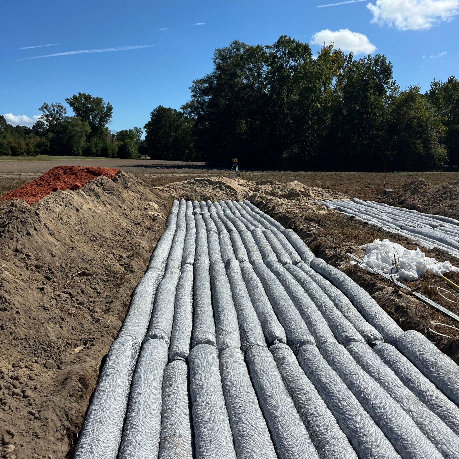 Man connecting hose to an orange septic truck; he is wearing gloves and smiling outdoors.