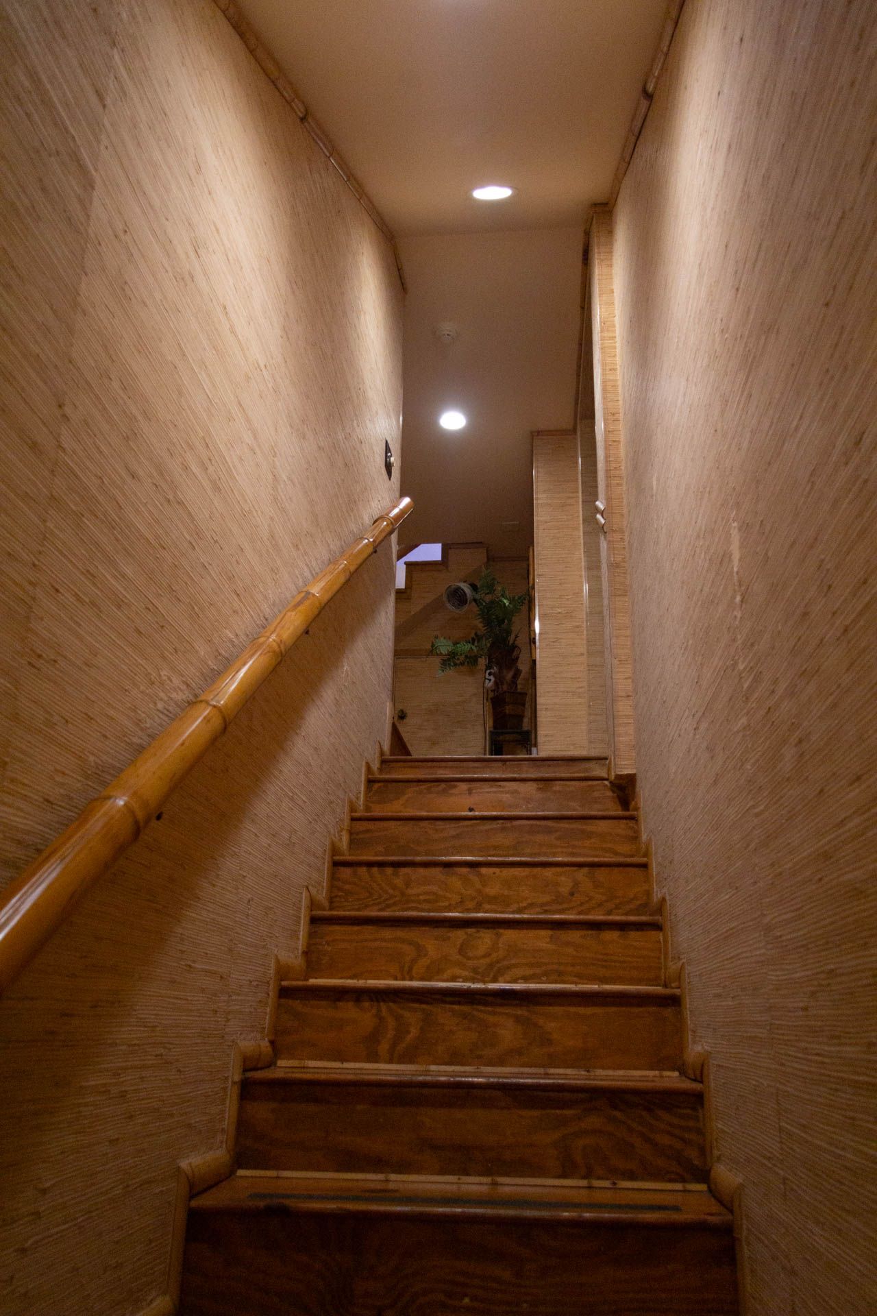 a set of wooden stairs leading up to a ceiling in a building .