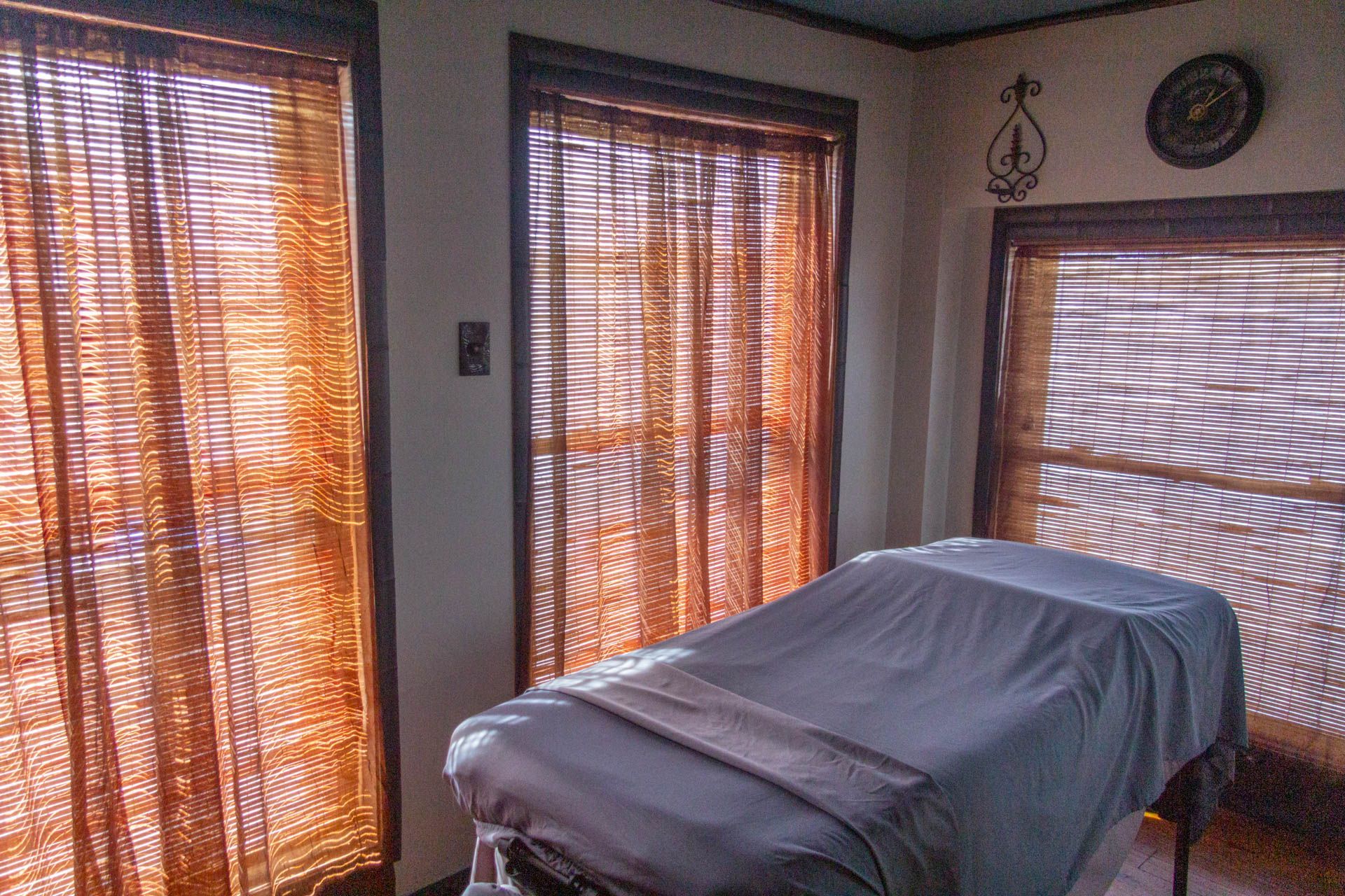 a massage table in a room with blinds on the windows