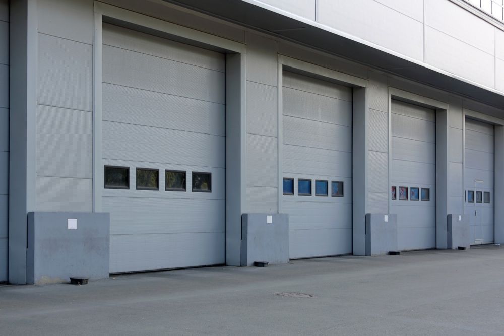 A Row Of Garage Doors With Windows On The Side Of A Building — Lighthouse Beach Garage Door Service in Lake Cathie, NSW