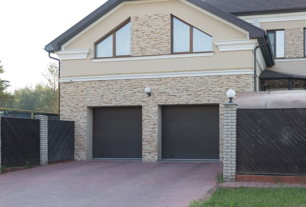A Large House With Two Garage Doors And A Driveway — Lighthouse Beach Garage Door Service in Bonny Hills, NSW