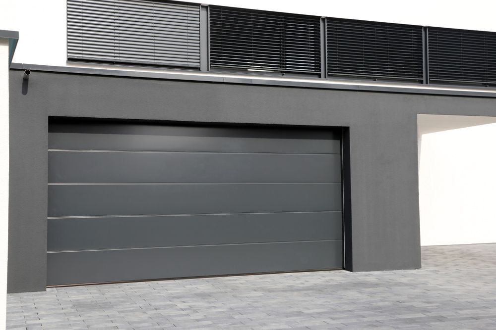 A Gray Garage Door With A White Building In The Background — Lighthouse Beach Garage Door Service in Wauchope, NSW