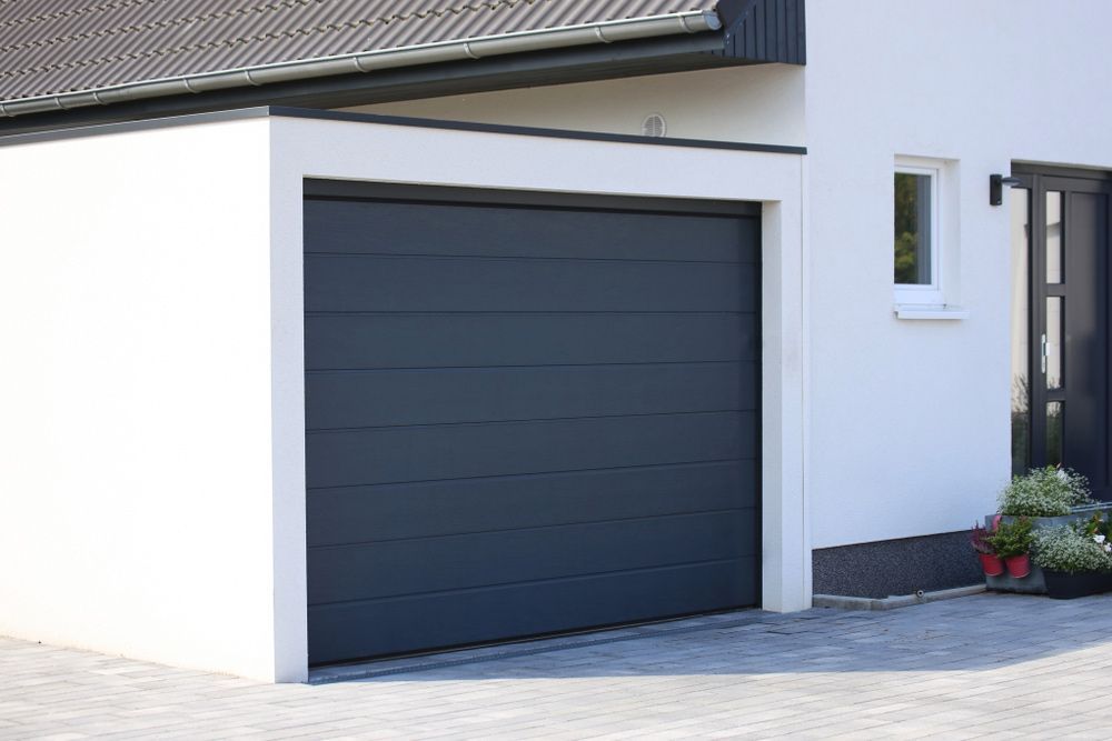 A Black Garage Door Is Installed  In Front Of A White House — Lighthouse Beach Garage Door Service in Port Macquarie, NSW
