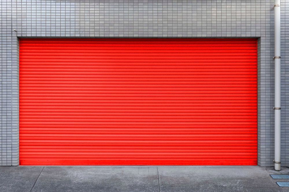 A Red Garage Door Is On The Side Of A Building — Lighthouse Beach Garage Door Service in Port Macquarie, NSW