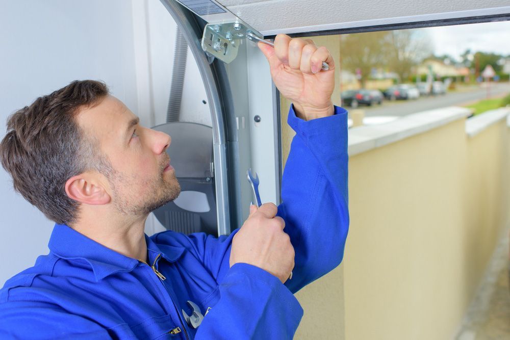 A Skilled Person Is Fixing A Garage Door With A Spanners — Lighthouse Beach Garage Door Service in Bonny Hills, NSW