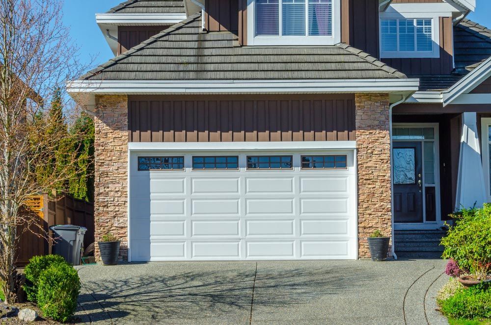 A Large House With A White Garage Door And A Driveway — Lighthouse Beach Garage Door Service in Port Macquarie, NSW