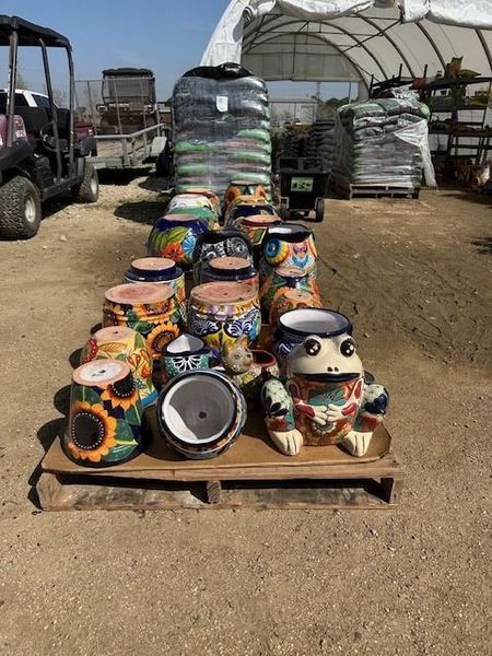 A bunch of colorful pots are sitting on a wooden pallet.