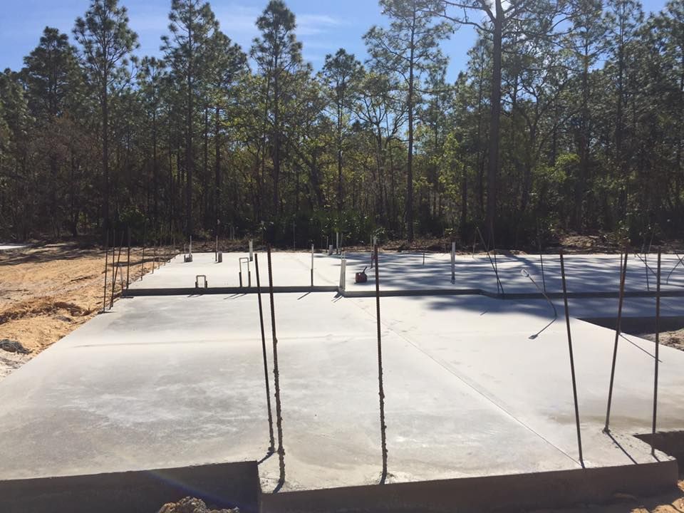 Concrete foundation with rebar protruding, trees in background.