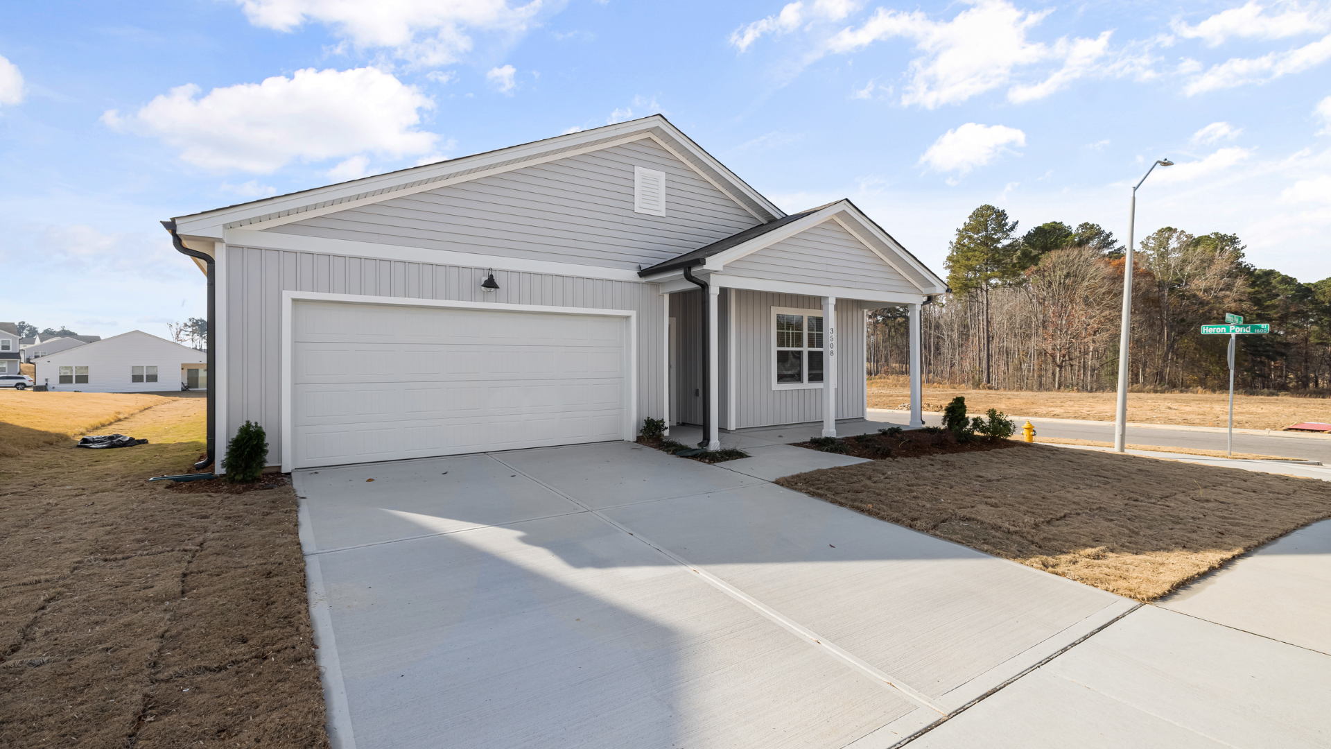Light gray house with a two-car garage and small front porch on a sunny day.