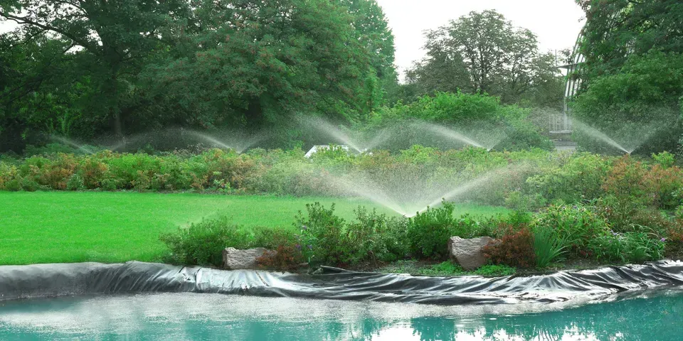 A sprinkler is spraying water on a lush green lawn.