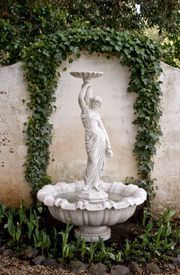 A fountain with a statue of a woman holding a bird feeder.