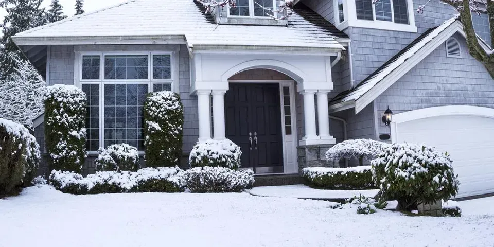 A house is covered in snow and there is a lot of snow on the ground.