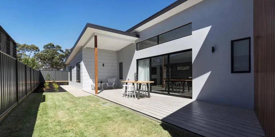 The backyard of a house with a table and chairs in it.