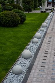 A row of white balls sitting on top of a gravel path.