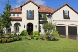 A large white house with a brown tile roof is sitting on top of a lush green lawn.