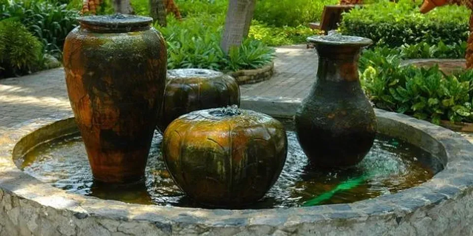 A fountain with three vases in it in a garden.