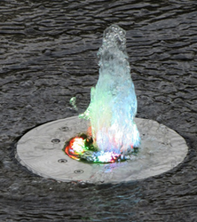A fountain with colorful lights on it is in the water.
