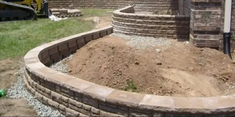 A brick wall is being built next to a pile of dirt.