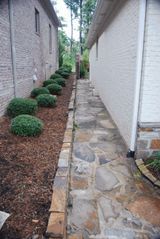 A stone walkway leading to the side of a house.