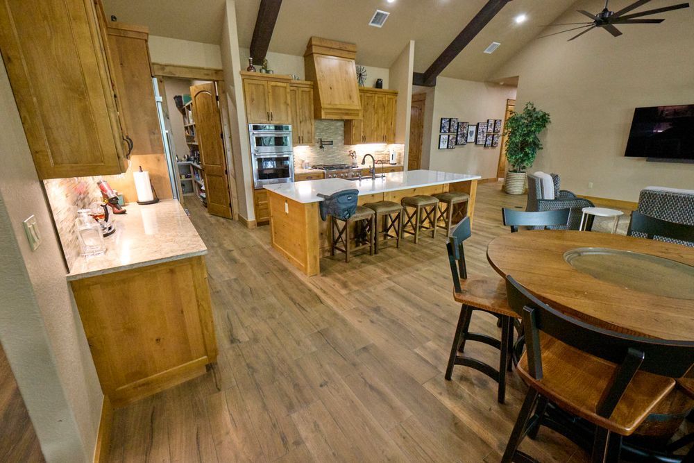 Modern kitchen and dining area with wooden cabinets, island seating, and a round table