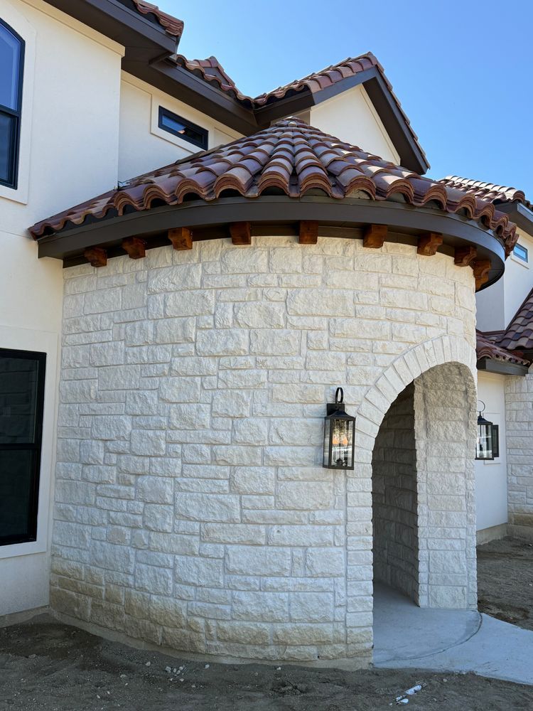 Stone stucco front entrance with arched doorway and red tile roof on a house exterior
