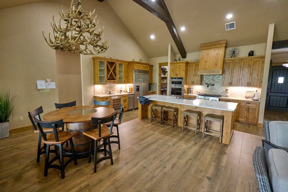 Modern kitchen and dining area with wood floors, island seating, and a round table under antler chandelier