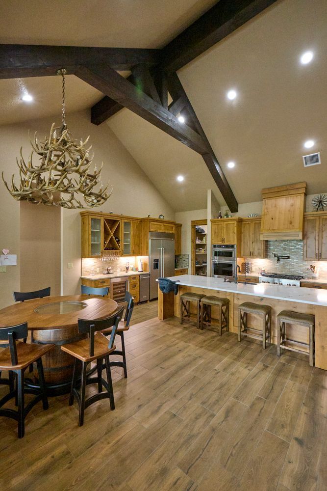 Spacious modern kitchen and dining area with wood floors, island stools, and a wooden chandelier