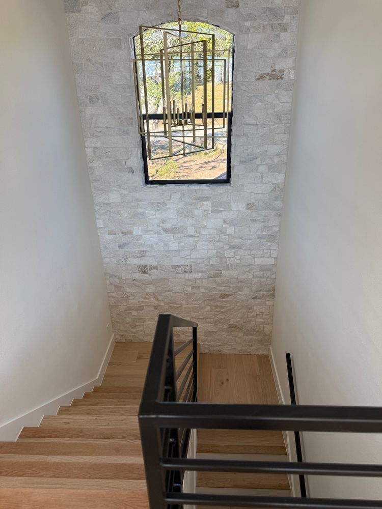 Stairwell with beige walls, black railing, and a small window at the landing.