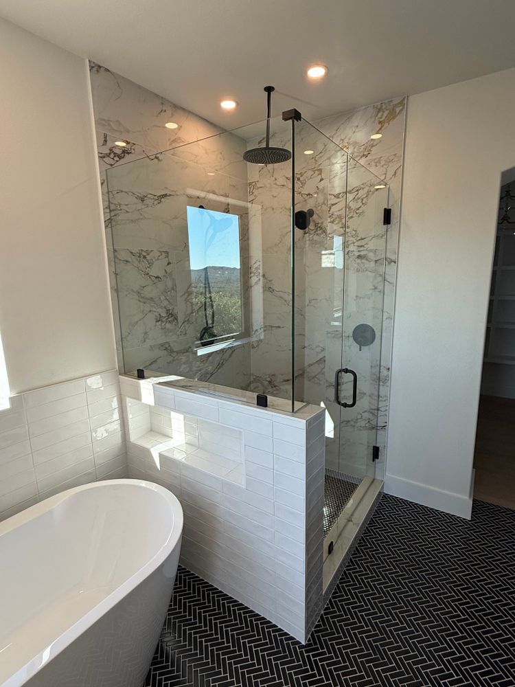 Modern bathroom with glass shower, white tile, freestanding tub, and black fixtures