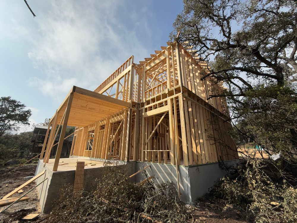 Partially built house with exposed wooden framing and concrete foundation under a clear sky