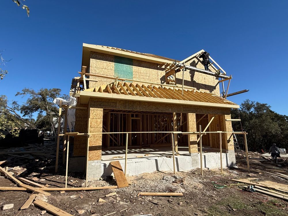 Partially framed house under construction with exposed wood and scaffolding on a sunny day