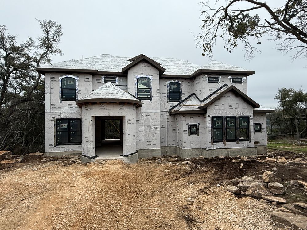 New two-story house under construction with stone facade and dirt driveway