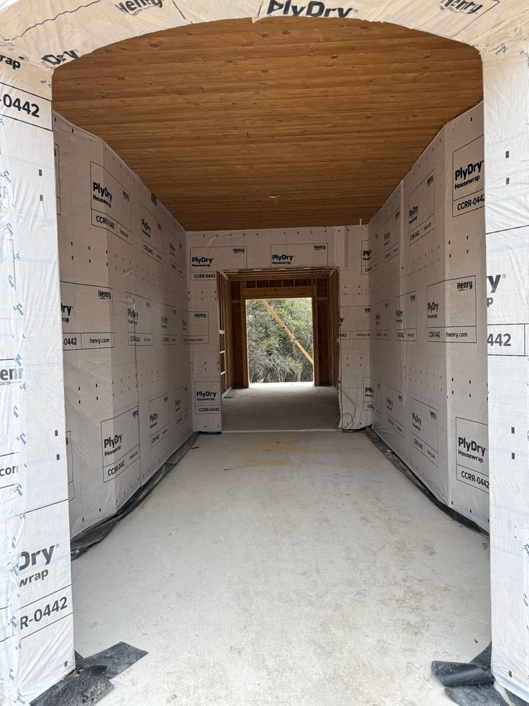 Narrow unfinished hallway under construction with drywall walls, wood ceiling, and concrete floor